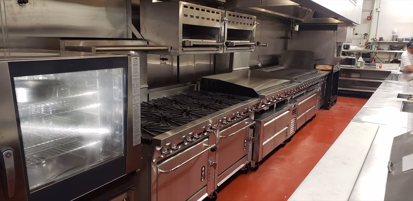 Long range and oven line installed on red quarry tile under a stainless hood